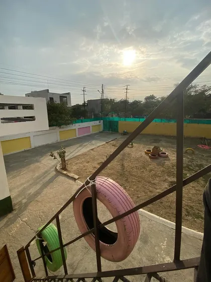 A view of our play yard from the stairs, showing the tires and open space under a sunny sky.