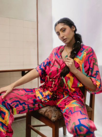 A close-up from the Advait 'Resort, 23' shoot, focusing on the vibrant pink co-ord set. We styled it with a unique braided hairstyle and a simple necklace to let the bold, abstract print of the outfit do the talking. This showcases our skill in resort wear styling.