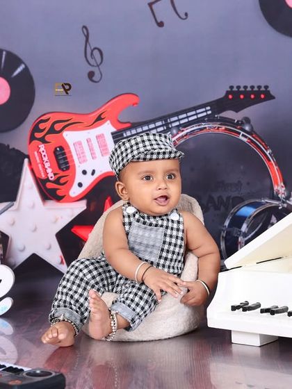 A baby sits by a mini piano, ready to create some tunes. The "ONE" sign and musical props make this a great theme for a first birthday.