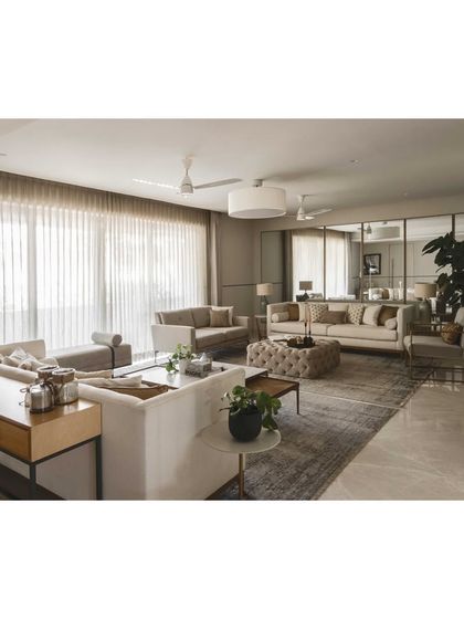 This wide shot shows the full living room layout, designed for easy conversation and flow. The neutral palette is calming, while the large plant adds a touch of nature.