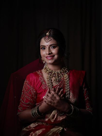 A classic bridal portrait of Madhurya. Her makeup features a bold red lip and defined eyes, a timeless choice for any bride.