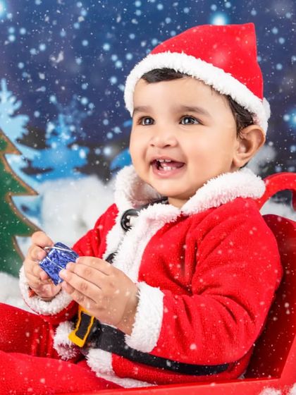 A happy little Santa playing with a toy in his sleigh. The falling snow effect adds a touch of magic.