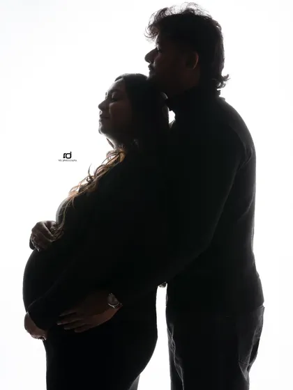 A strong and serene silhouette portrait. The husband stands behind, protectively embracing his wife, symbolizing their partnership on this journey.