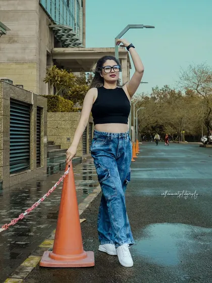 This shot for a denim brand uses an everyday traffic cone as a prop to add a pop of color and an element of spontaneous street style. The pose is confident and relaxed, capturing the brand's youthful energy.