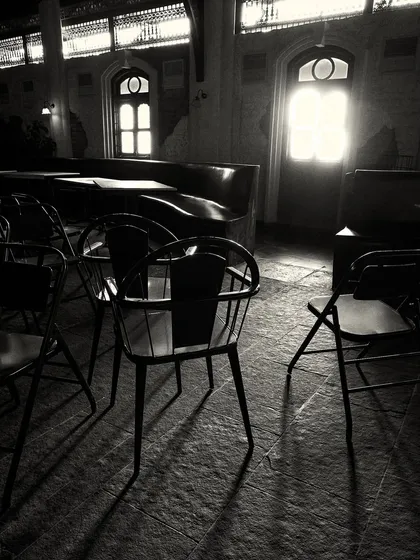 The silhouette of a chair against the light from a distant doorway, capturing the moody and atmospheric quality of the interior.