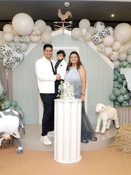 The happy family celebrating Vyom's first birthday in front of the beautiful farm-themed backdrop I designed.