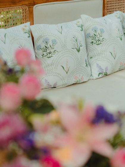 A close-up of the pastel floral arrangements and custom-printed cushions that added a soft, romantic touch to the Mehendi seating.