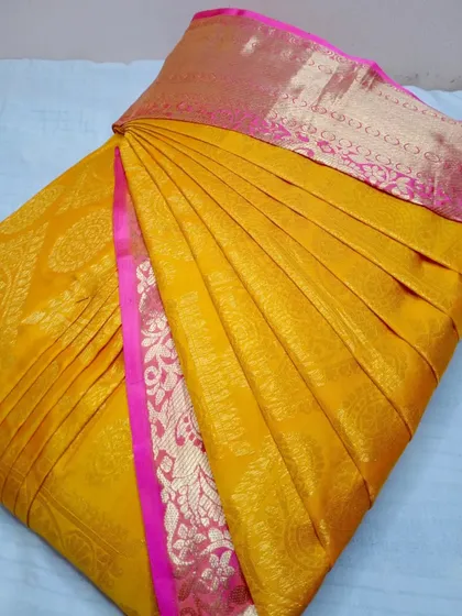 A bright yellow and pink silk saree, pleated and ready to flaunt.