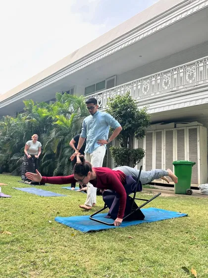 Guiding a student from the USA through a balancing pose using a chair for support. My goal was to give them an authentic, deep experience of yoga on their spiritual journey through India.