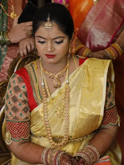 A serene moment before the ceremony. This bride is the picture of grace in her golden Kanjeevaram saree, with makeup that gives her a warm, radiant glow.