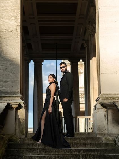 A powerful, statuesque pose against London's classic architecture. Their all-black, coordinated formal wear creates a dramatic and sophisticated look for their pre-wedding shoot.