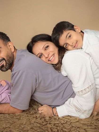 A playful family pile-up. This fun and creative pose is a wonderful way to get a unique family portrait with a newborn, showing the love and connection between everyone.