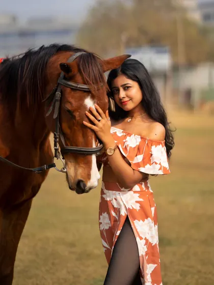 A model in a floral dress poses with a horse, a perfect example of a summer or spring-themed fashion shoot at my location.