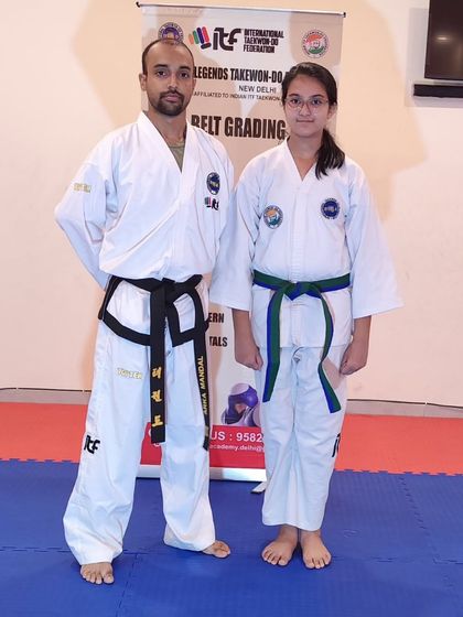 A female student is awarded her green-stripe belt, showing her consistent progress and commitment.