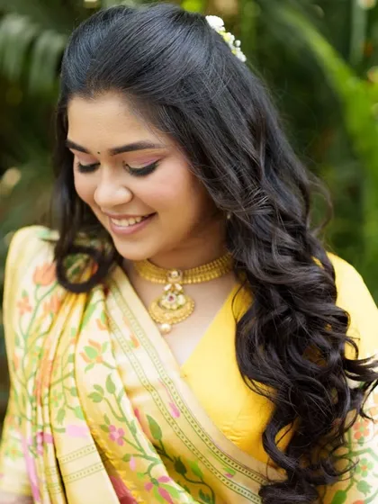 An eyes-closed shot showing the soft, shimmery eye makeup that complements the yellow and pink tones of her outfit.