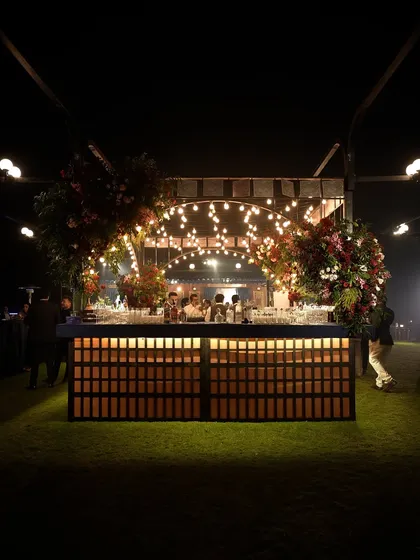 The magnificent island bar we designed for the "Golden Rails" event. The backlit wooden base, string bulb canopy, and lush floral arrangements made it a central hub of the celebration.