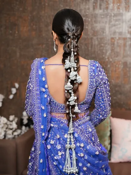 I love adding a modern twist to traditional hairstyles. This stunning silver-accented braid is a perfect example, designed to complement the rich blue hues of the lehenga. It's a unique and elegant statement for any bridal function.