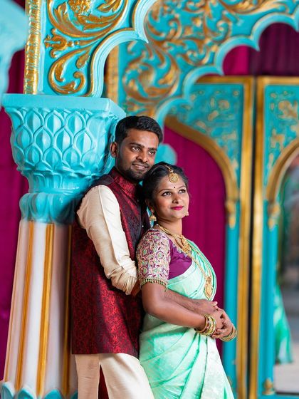 An elegant pre-wedding portrait of a couple in coordinated ethnic wear, posing against a vibrant, decorative backdrop that complements their traditional attire.