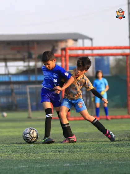 A young player shielding the ball from an opponent, showcasing strength and game intelligence.