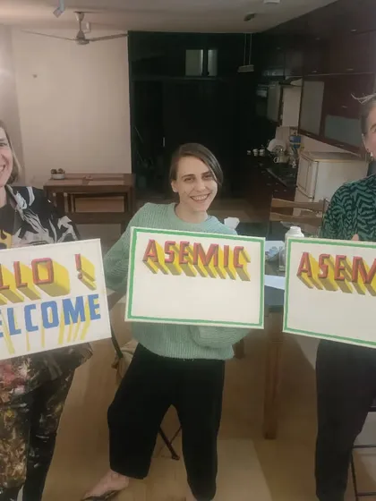 Two signs for international clients, one saying "Hello Welcome" and the other "Asemic," both in a clean, multi-colored 3D style.