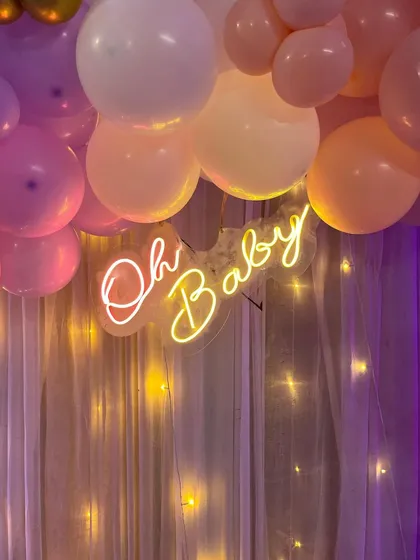 A close-up of the 'Oh Baby' neon sign against a backdrop of fairy lights.