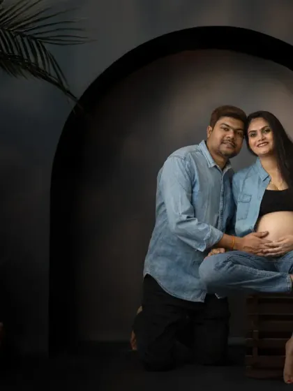 A stylish maternity portrait using a modern arched prop. The casual denim outfits and moody lighting create a sophisticated and contemporary look.