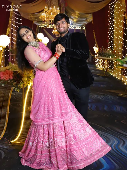 This happy couple is all smiles, with her in a vibrant pink lehenga. It's the perfect outfit for a fun and festive wedding event.