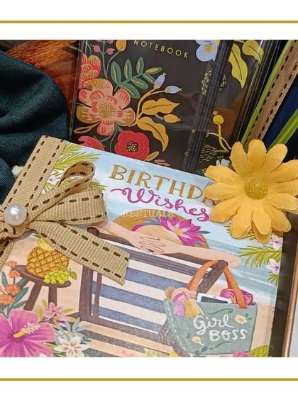 A close-up of the 'Birthday Wishes' card and floral notebook from the hamper.