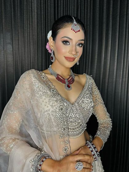 My lovely Sagan bride, looking absolutely radiant. This look features a silver-toned lehenga with ruby jewelry, complemented by soft pink makeup and a delicate bindi.