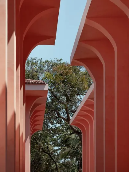 The streetscapes of Baia are designed to be experienced on foot, with asymmetrical alleyways and vertical fins that curve like tree branches. This perspective through the repeating arches frames the natural surroundings, creating a pocket-sized glimpse of a Portuguese town.