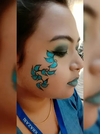 A different angle of the blue fantasy makeup, highlighting the glitter detail on the hand-painted leaves. Our students learn to use various materials like cosmetic glitter to add dimension to their work.