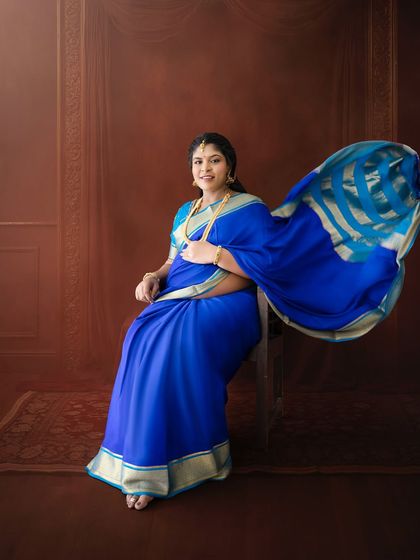A dynamic shot capturing the beautiful movement of a blue saree's pallu as the mom-to-be sits elegantly for her portrait.