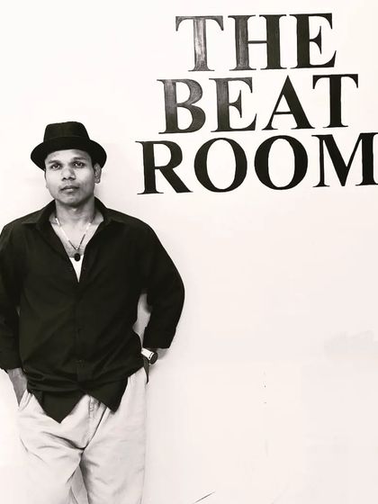Instructor Trilochan posing next to The Beat Room logo. This studio is our passion and our dream come true.