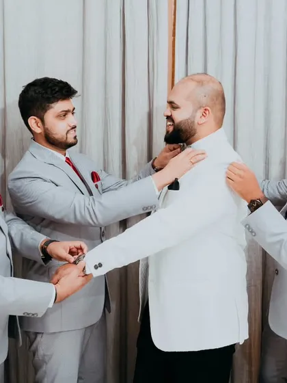 The groomsmen helping the groom with the final touches on his suit, a great candid moment of friendship and support.