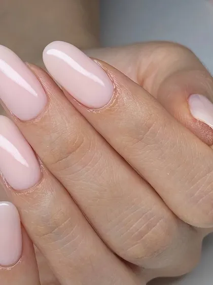 A classic, elegant nude pink manicure on long, oval-shaped nails. This timeless look is perfect for any occasion, from everyday wear to special events.