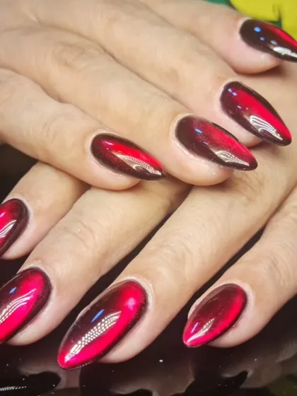 A dramatic red and black cat-eye design on almond nails, creating a fiery, magnetic effect.