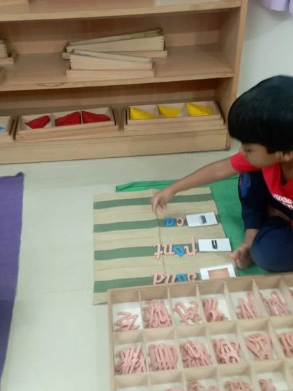 The Movable Alphabet empowers children to "write" words even before their hands are ready to hold a pencil. This child is building words on a mat, physically manipulating the letters to express his thoughts.
