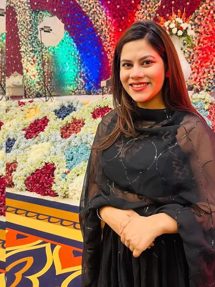 A simple and elegant all-black look for an event with a stunning multi-colored floral backdrop.