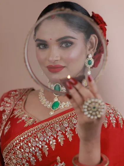 The iconic Karva Chauth pose, looking through the sieve. The makeup is classic and elegant.