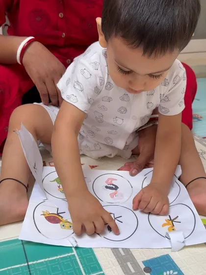 A toddler carefully points to the correct animal, showing his focus and understanding. These simple matching games are excellent for cognitive development.
