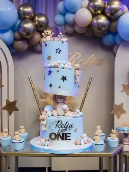 A close-up of the stunning three-tiered cake from the teddy bear themed first birthday party. The cake is perfectly coordinated with the pastel blue decor and adorable bear figures.