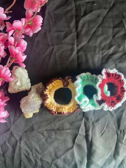 This image shows the scrunchies lined up, highlighting the detailed crochet work on the ruffled edges. These are a great way to add a pop of custom color to your hairstyle.