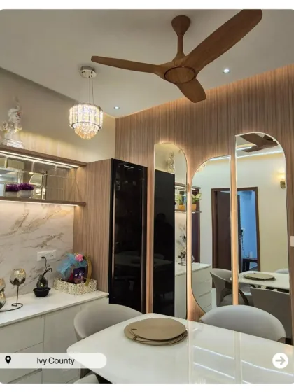 A dining area that feels open and connected to the living space. The design uses wood paneling, mirrors, and a modern chandelier to define the space beautifully.