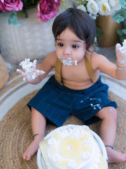 Hands full of cake and a face full of joy. This is the perfect moment from a fun and messy first birthday cake smash.