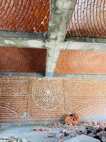A work-in-progress shot of a yoga classroom featuring various brick patterns. The walls and ceilings are adorned with different styles of brick domes and decorative masonry, creating a space designed to inspire wellness and meditation.