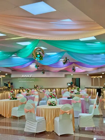 A wide view of the banquet hall, decorated with a ceiling of pastel drapes and beautifully set tables.
