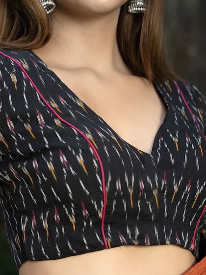 Another look at our black ikat blouse. The V-neck is accentuated with subtle pink piping, adding a pop of color to the traditional handloom fabric.