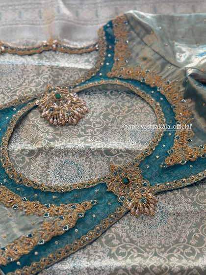 A teal blouse with a sheer back and a large circular cutout, framed with heavy zardosi work.