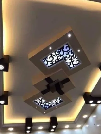This design features floating panels with backlit jali cutouts, creating a modern yet decorative look. The combination of spotlights and cove lighting provides ample and beautiful illumination.