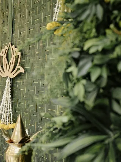 A close-up of the backdrop, featuring a woven green mat with wooden lotus cutouts and delicate floral tassels.